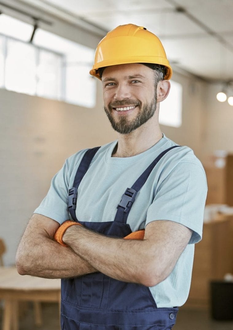 cheerful-male-worker-in-helmet-standing-in-workshop-e1706450194722.jpg